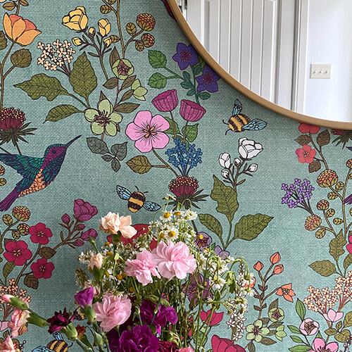 hummingbird and flower wallpaper on an accent wall with a mirror and bouquet of fresh-cut flowers
